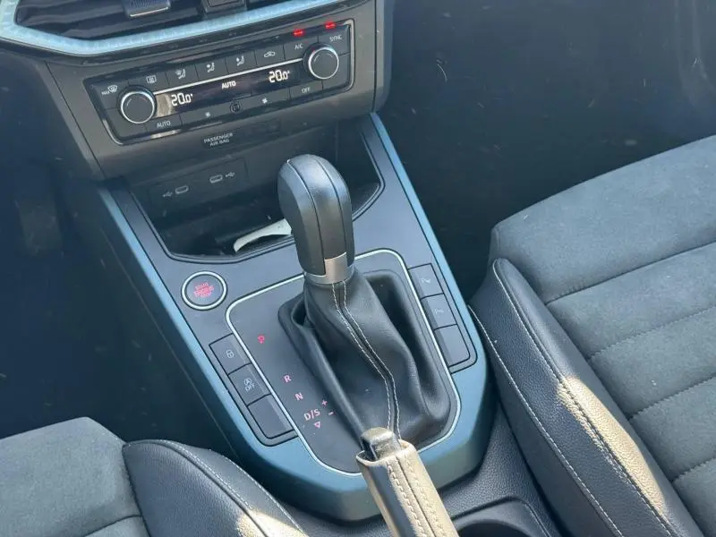 Gros plan sur la console centrale noire du SEAT Arona 2025, mettant en valeur le levier de vitesse automatique et la climatisation.