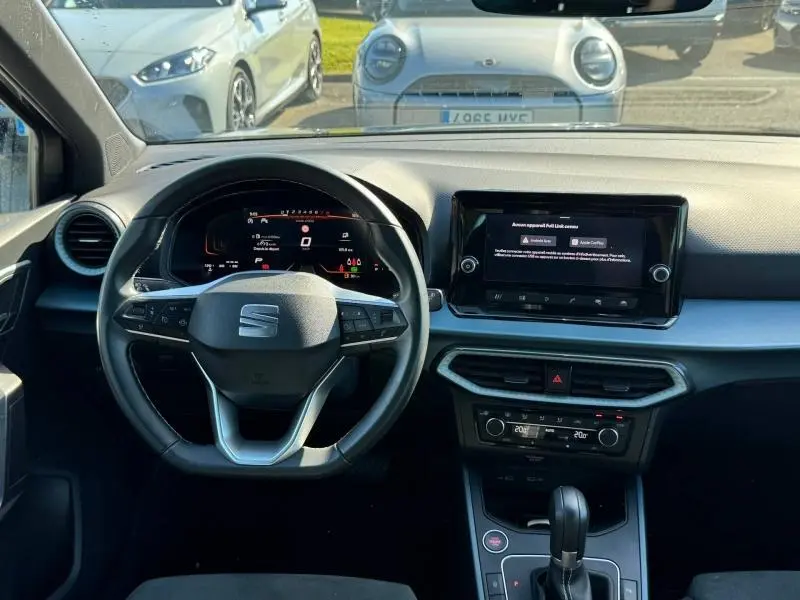 Vue intérieure frontale du tableau de bord et volant cuir multifonction de la SEAT Arona noir 2025 avec écran tactile central.