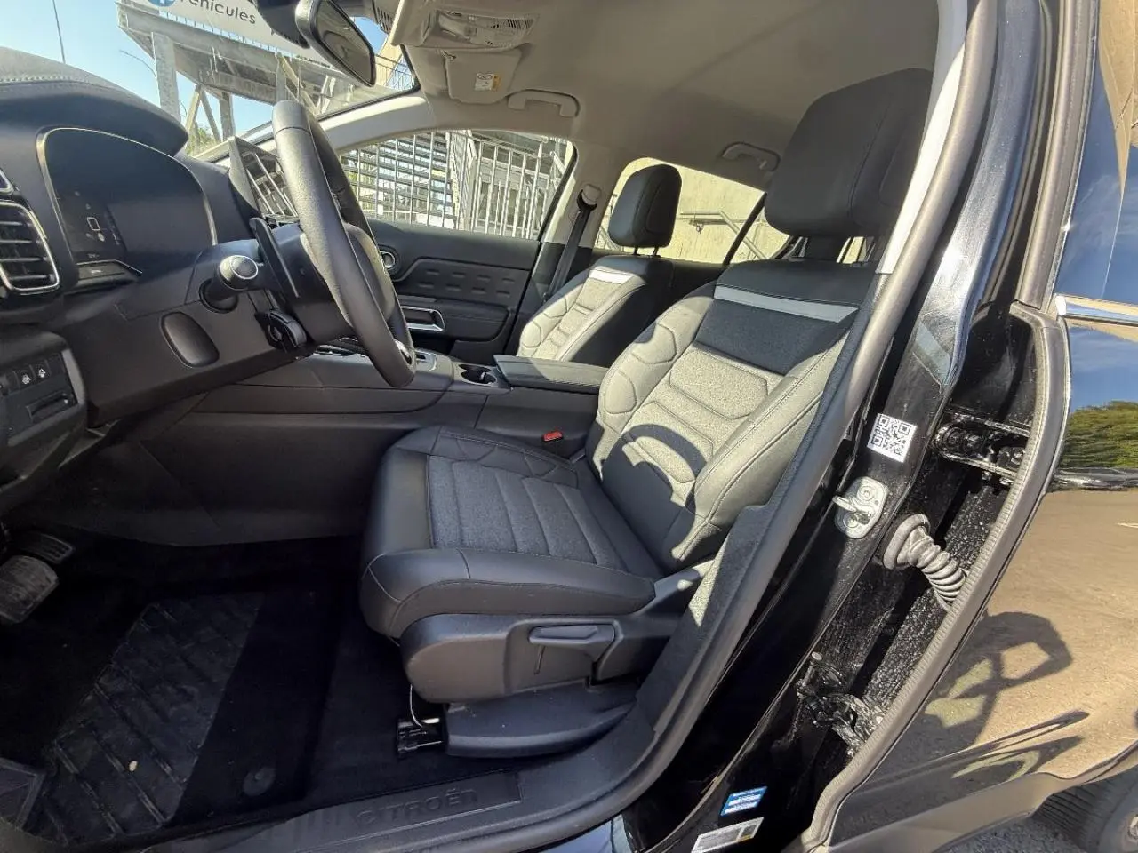 Vue intérieure côté conducteur du Citroën C5 Aircross 2024 artense, montrant les sièges et le tableau de bord noirs.