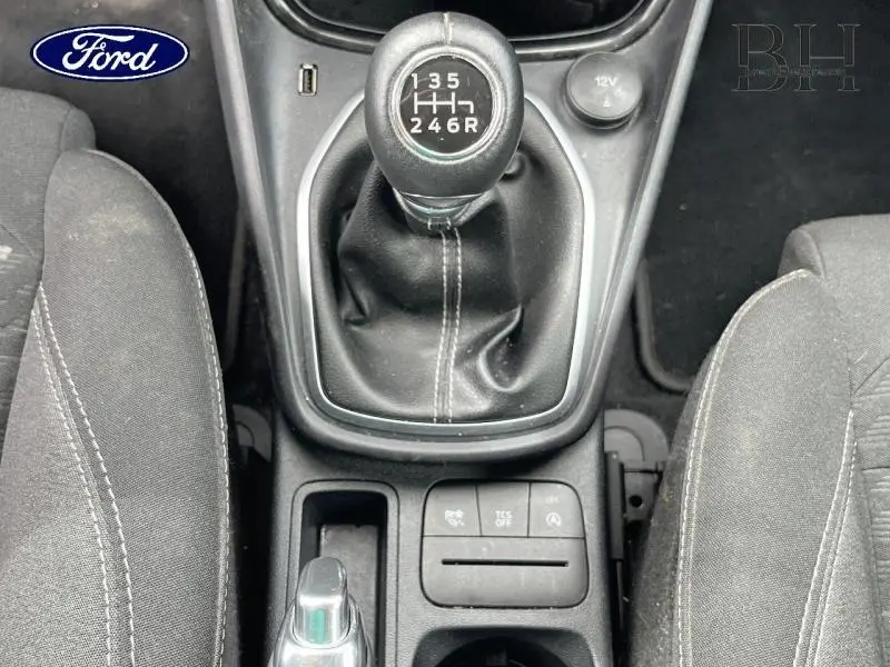 Vue rapprochée de la console centrale avec levier de vitesses manuel noir et sièges tissu gris du Ford Puma bleu.