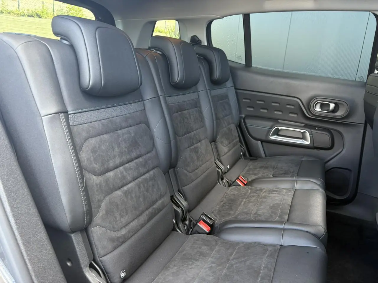 Vue latérale droite des trois sièges arrière en Alcantara noir du Citroën C5 Aircross 2025, avec porte et fenêtre visibles.