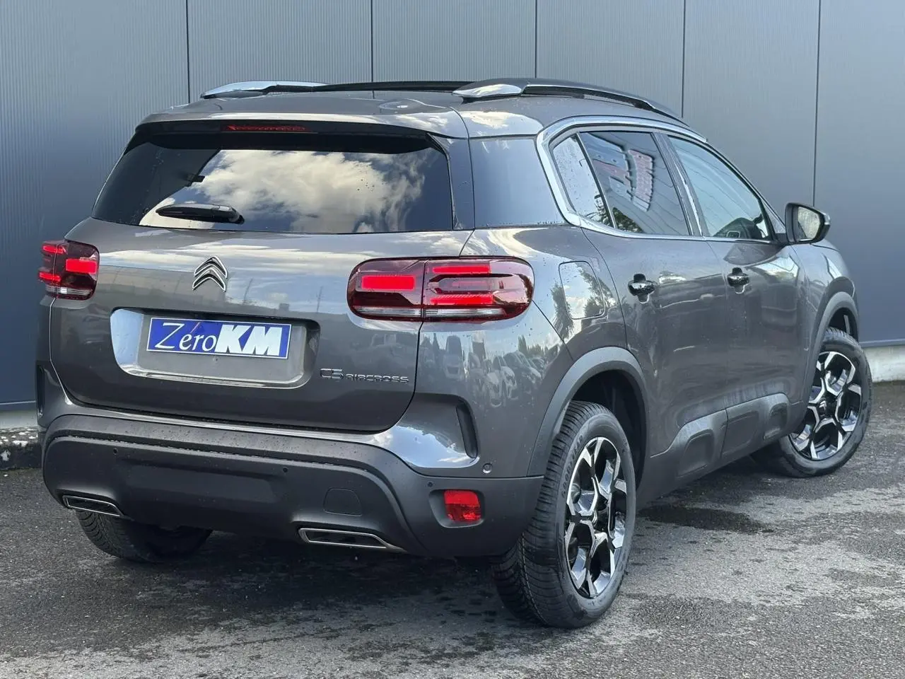 Vue 3/4 arrière droite d'un Citroën C5 Aircross gris Platinium avec jantes diamantées et toit ouvrant panoramique.