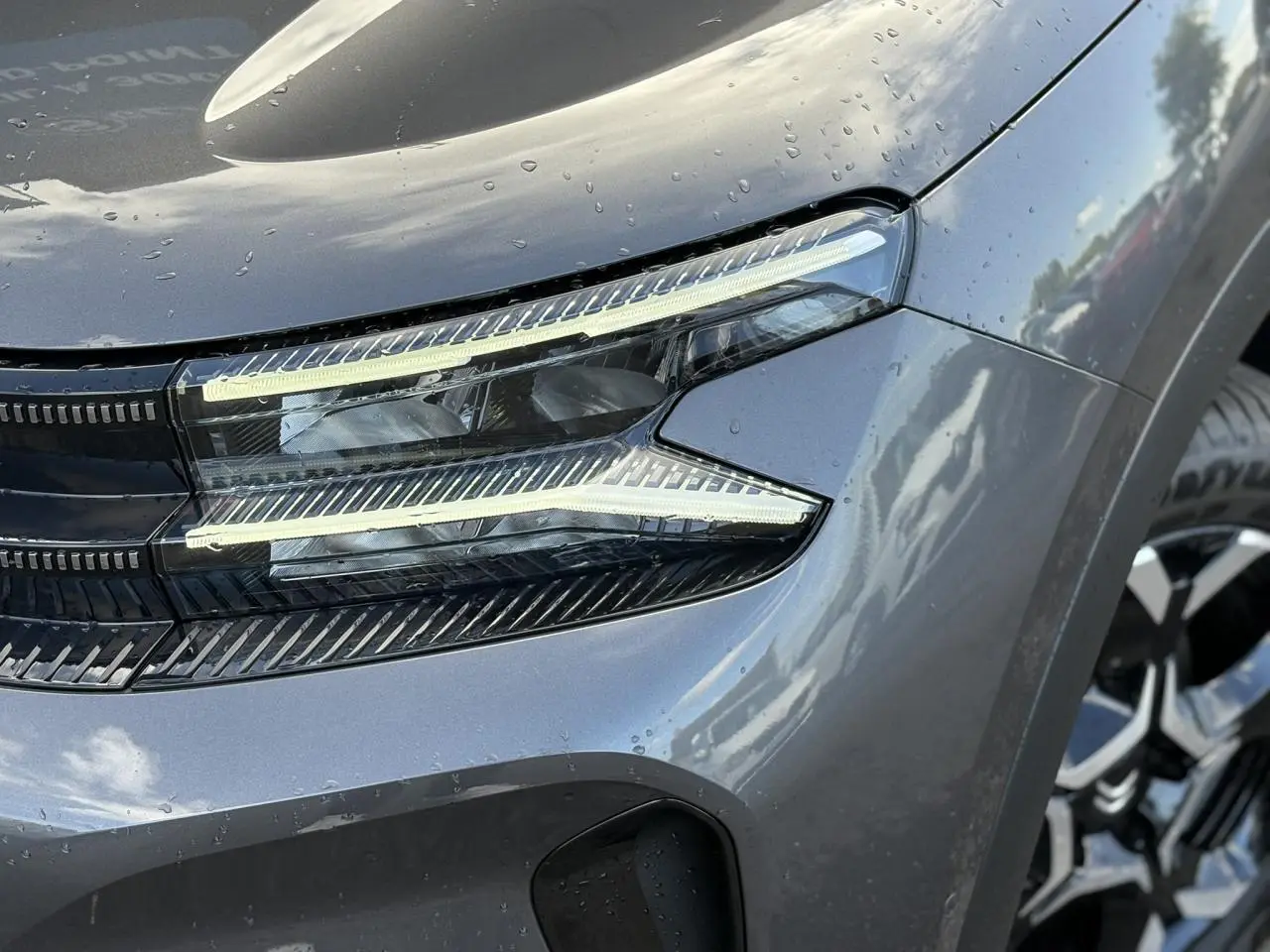 Gros plan sur le phare avant droit du Citroën C5 Aircross gris Platinium avec jante alliage visible en arrière-plan.