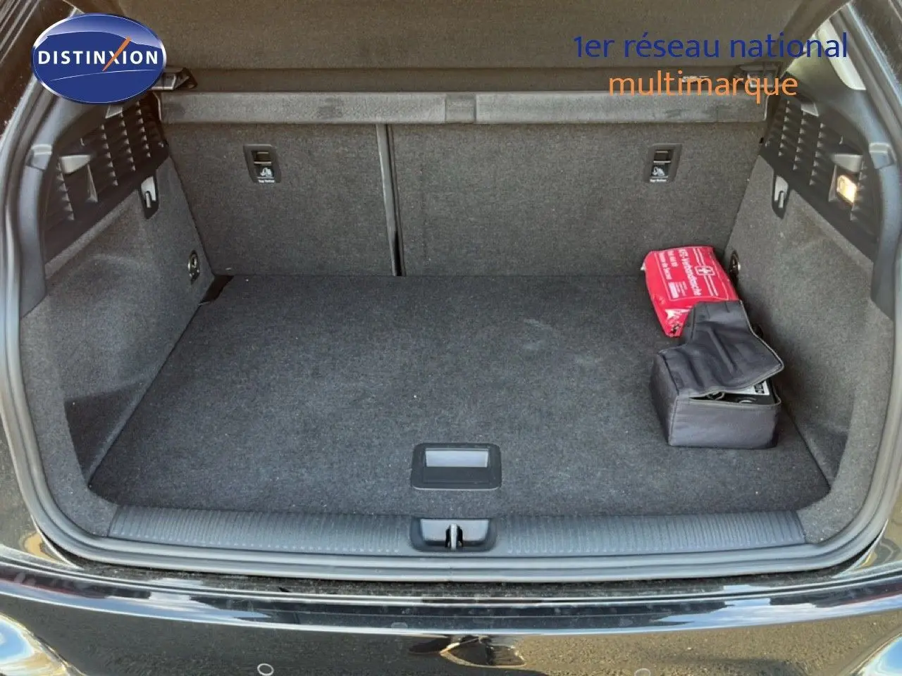 Coffre ouvert de l'Audi Q2 noir mito metal 2023, montrant un espace de chargement propre avec trousse de secours rouge.