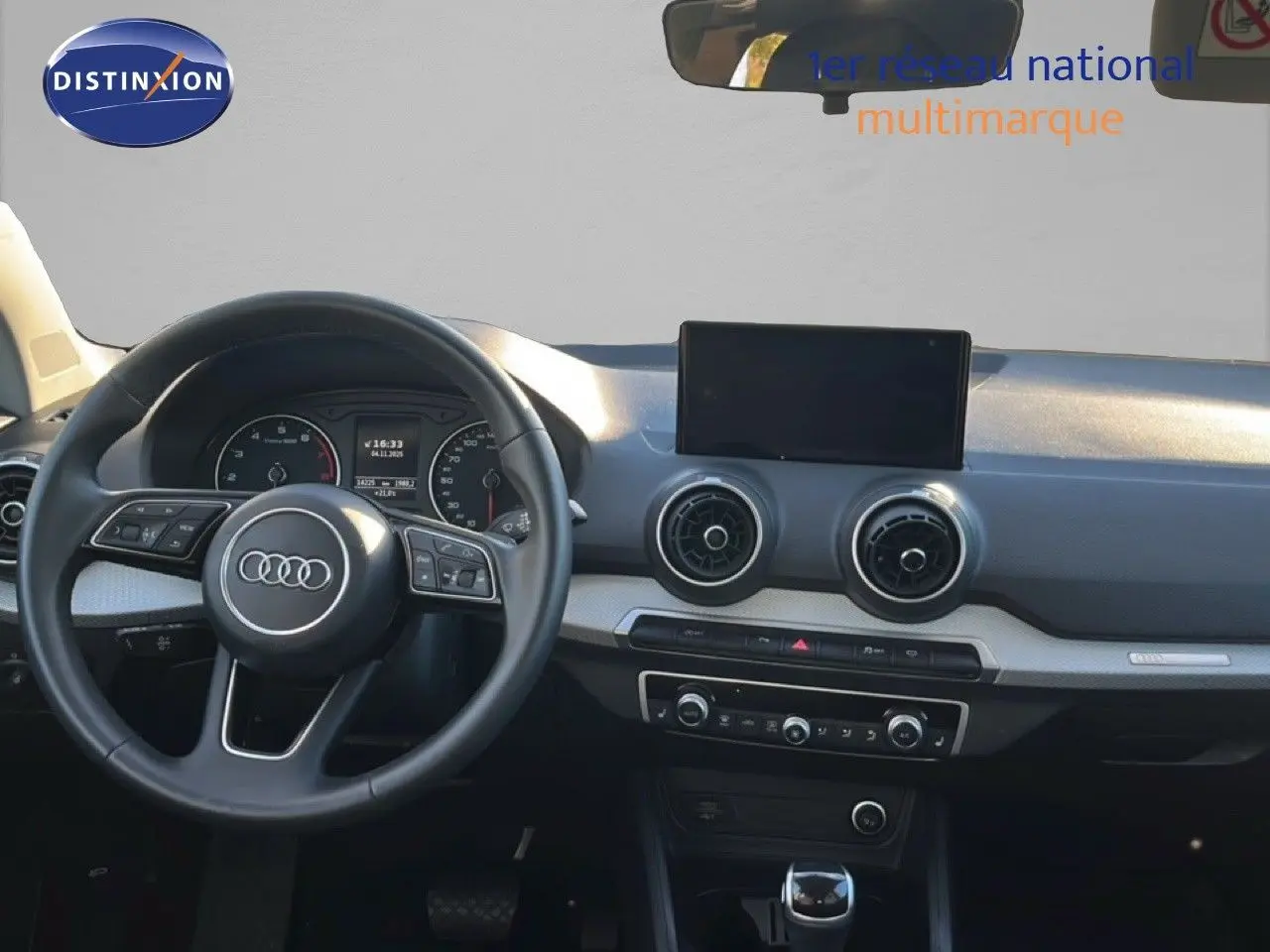 Intérieur d'Audi Q2 35 TFSI 2023, vue frontale du tableau de bord avec volant noir et écran central.
