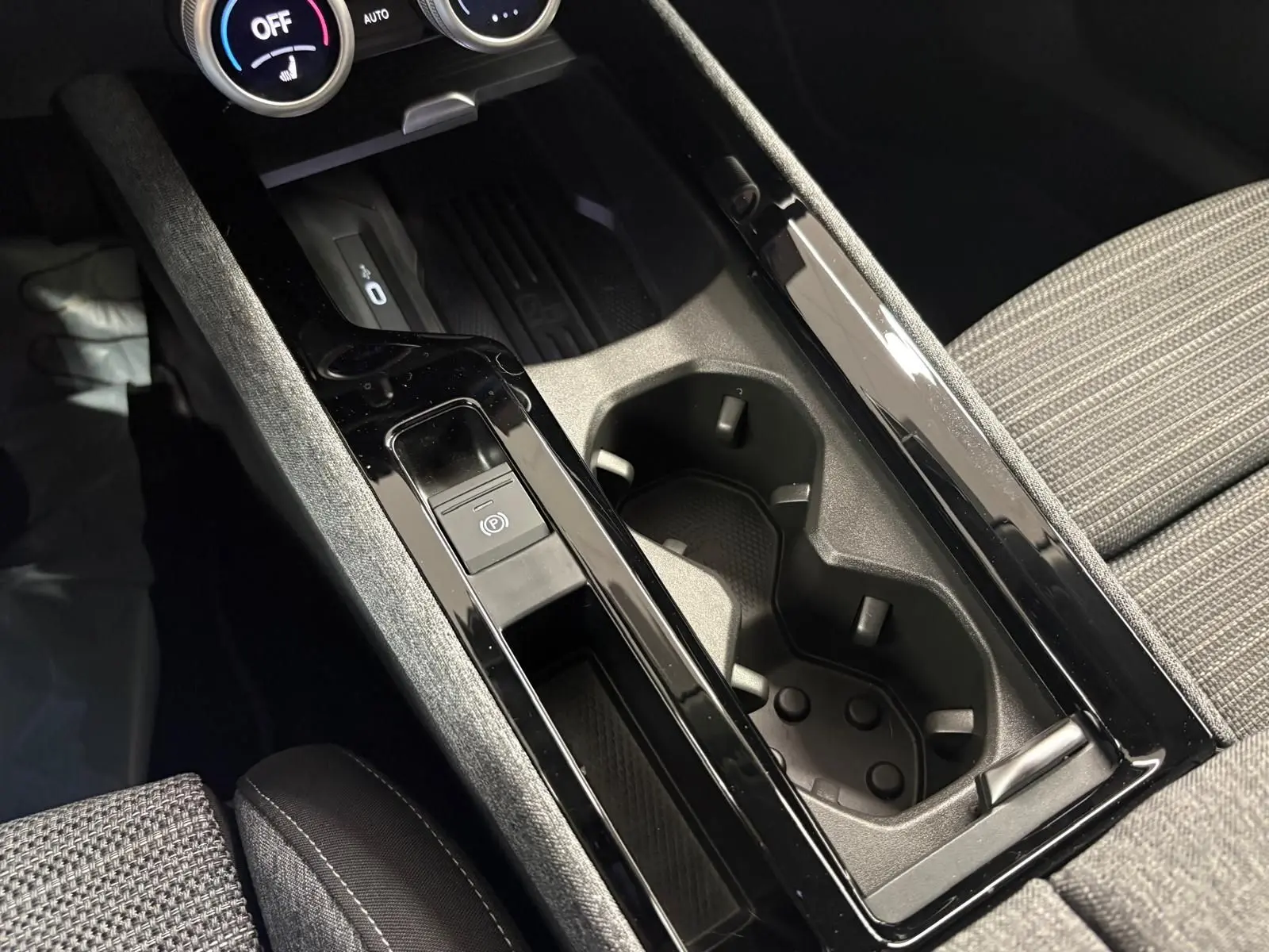 Gros plan sur la console centrale noire et grise du Skoda Superb Combi 2025, avec porte-gobelets et bouton frein à main électrique.