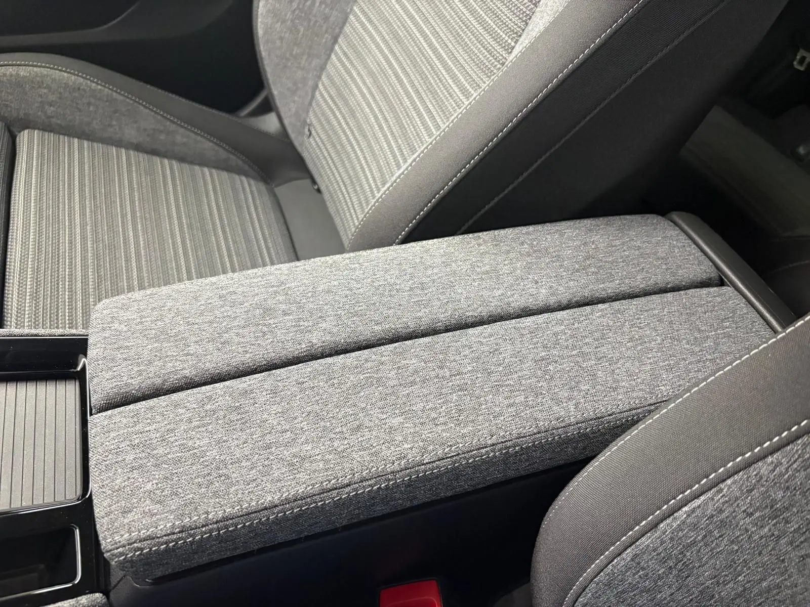 Détail de l'accoudoir central et siège avant en tissu gris à motifs, intérieur du Skoda Superb Combi 2025.