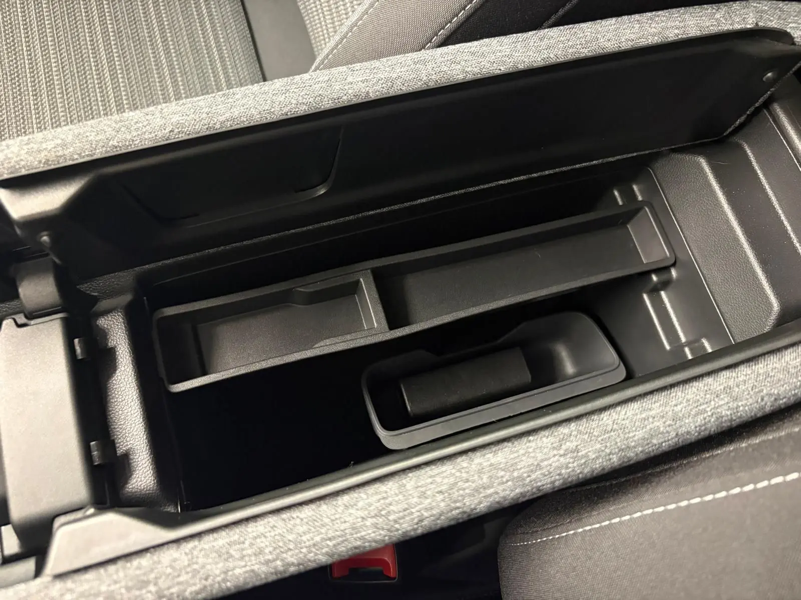 Vue rapprochée de l'intérieur de la console centrale ouverte d'une Skoda Superb Combi gris argent 2025.