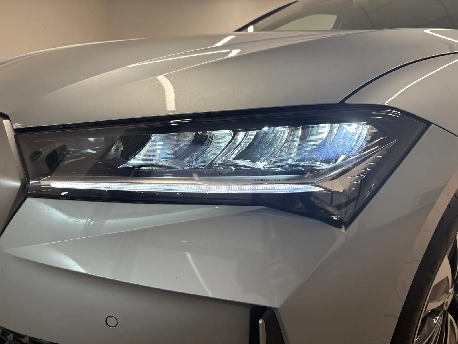 Gros plan sur le phare avant droit du Skoda Superb Combi gris argent 2025 avec éclairage LED distinctif.