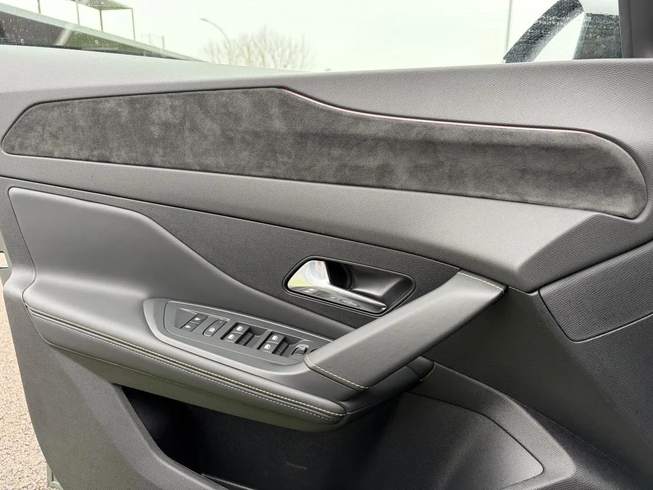 Gros plan sur la porte avant gauche de la Peugeot 308 gris sélénium, avec surpiqûres vert Adamite et insert en alcantara.