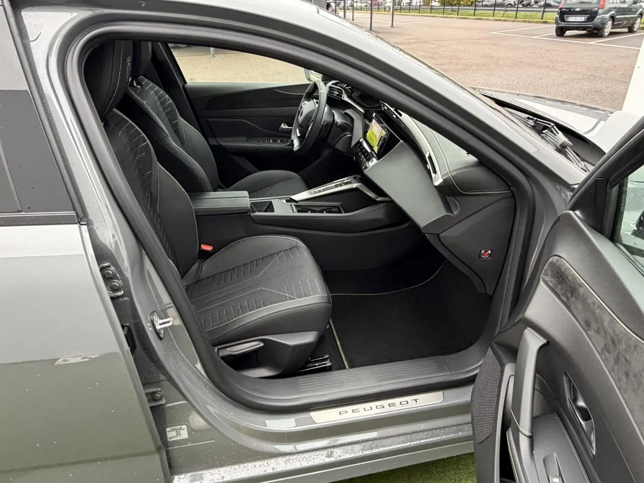 Vue intérieure côté conducteur de la Peugeot 308 gris selenium, montrant sièges noirs et tableau de bord moderne.