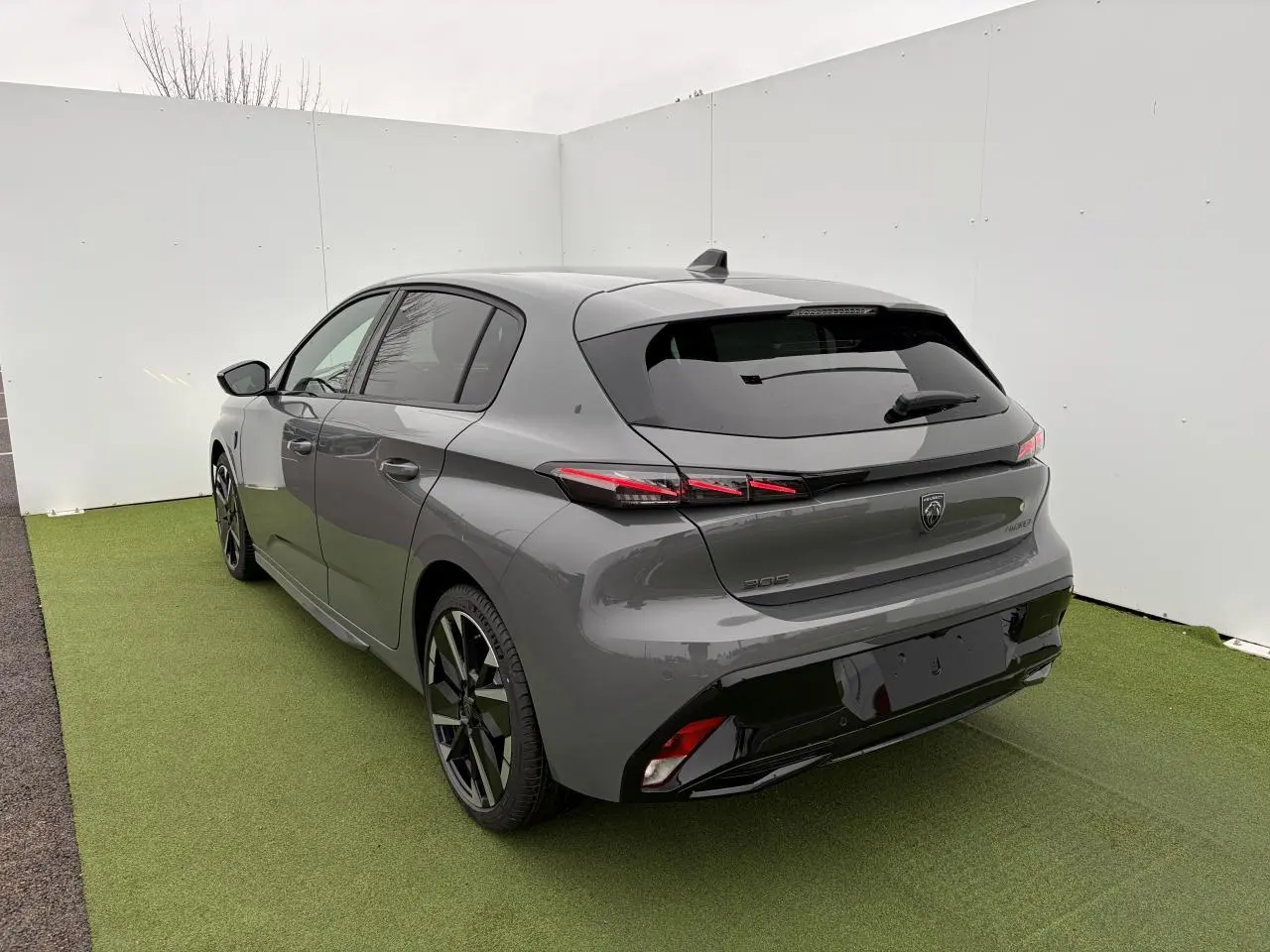 Vue 3/4 arrière droite d'une Peugeot 308 gris selenium avec feux arrière LED en forme de griffes et jantes alliage bi-tons.