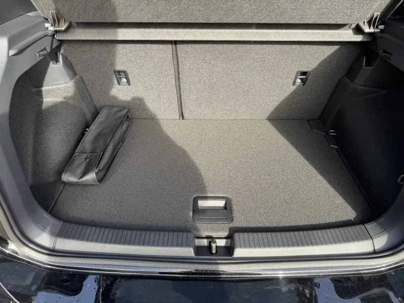 Coffre ouvert vu de face du Volkswagen T-Cross 2025 noir intense nacré, montrant un espace de chargement propre et un rangement latéral.