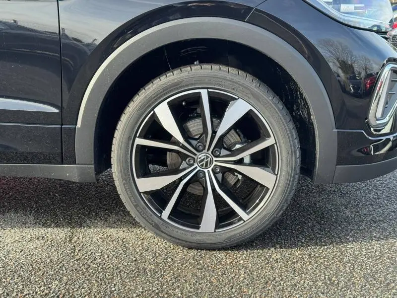 Gros plan sur la roue avant droite du Volkswagen T-Cross 2025 noir intense nacré avec jante alliage R-Line à dix branches.