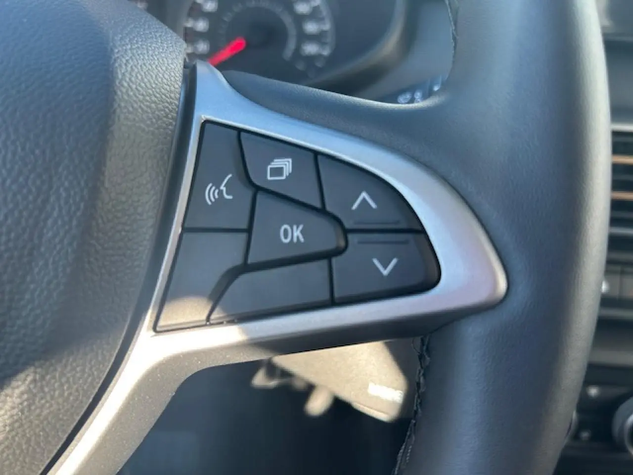 Gros plan sur les commandes multifonctions à droite du volant noir du Dacia Sandero III Stepway 2025.