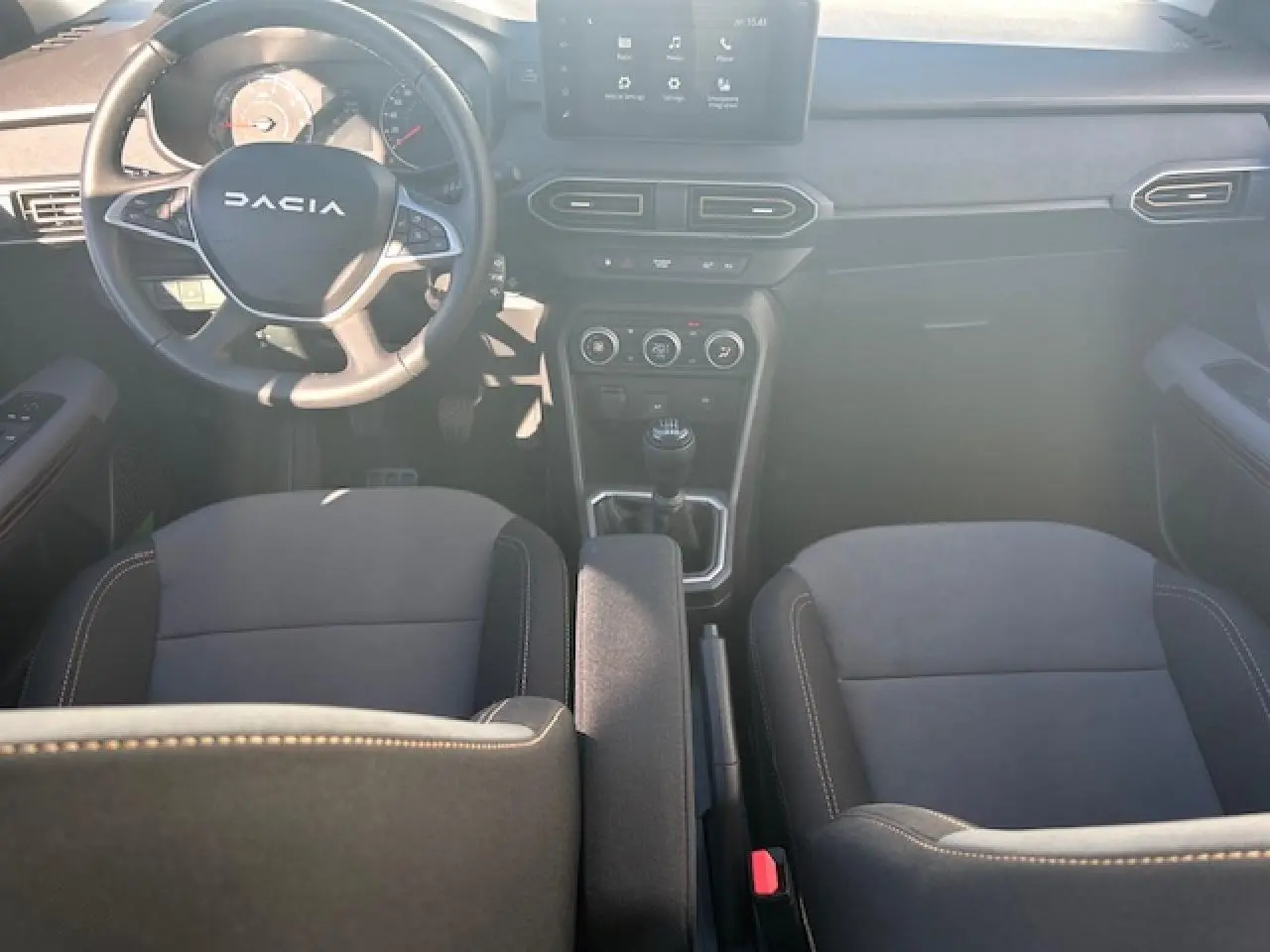 Vue intérieure avant de la Dacia Sandero III Stepway noire nacrée, volant, écran tactile et levier de vitesses manuel visibles.