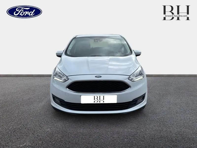 Vue de face d'une Ford C-MAX blanche Glacier avec calandre noire et phares halogènes allumés.