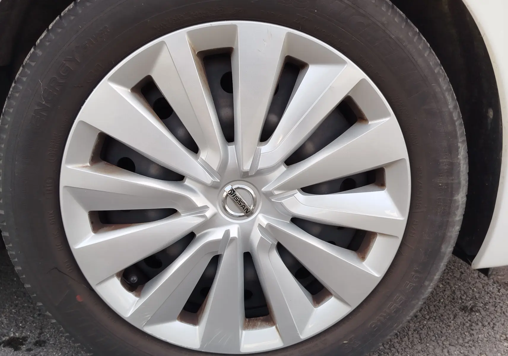 Gros plan sur la jante argentée d'une Nissan Micra blanche de 2019, mettant en valeur le logo central Nissan.