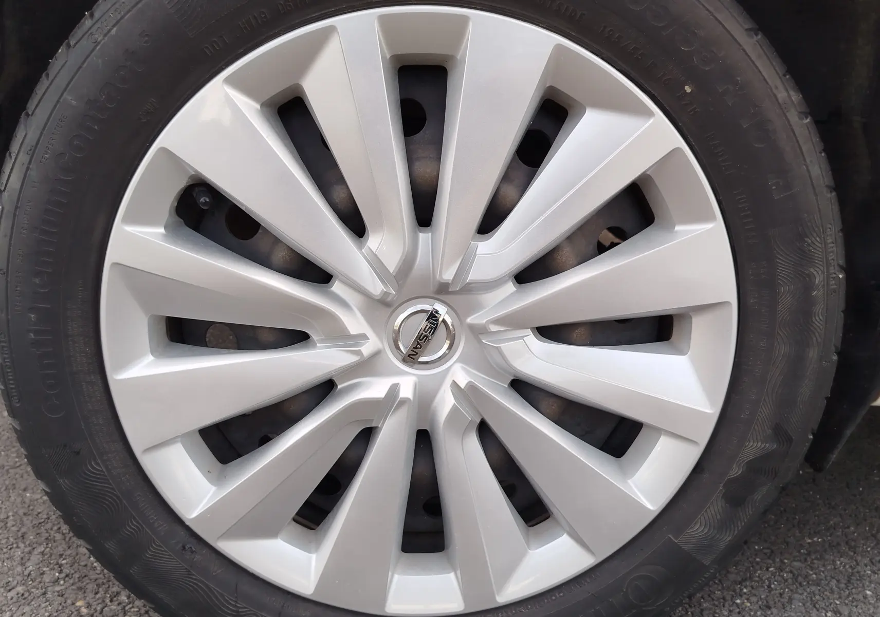 Gros plan sur la jante argentée d'une Nissan Micra blanche de 2019, avec logo Nissan au centre.