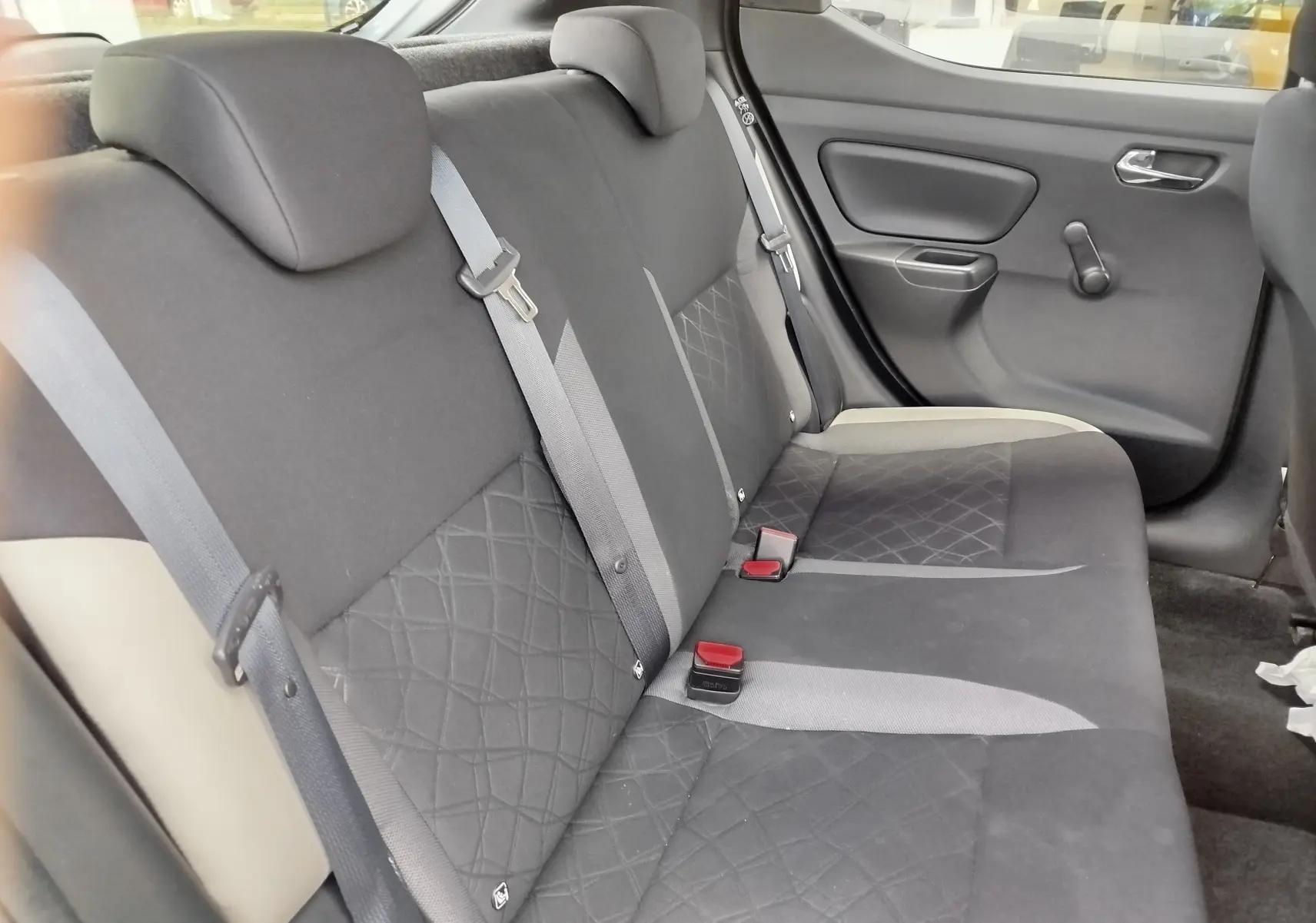 Vue du siège arrière côté droit de la Nissan Micra 2019, tissu gris avec motifs losanges et ceintures visibles.