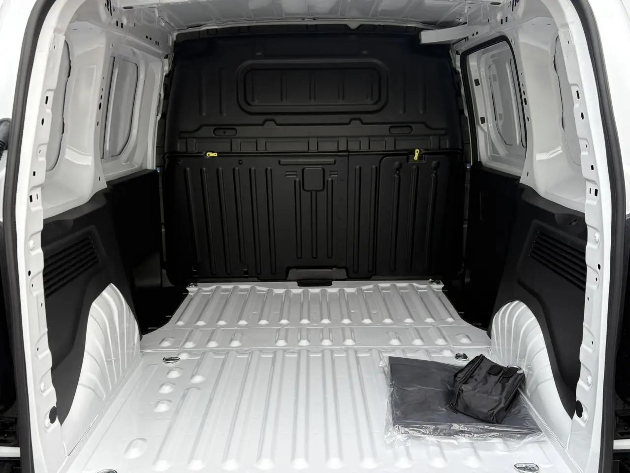 Vue intérieure arrière du Citroën Berlingo blanc Icy, montrant la zone de chargement tôlée et un kit de protection au sol.