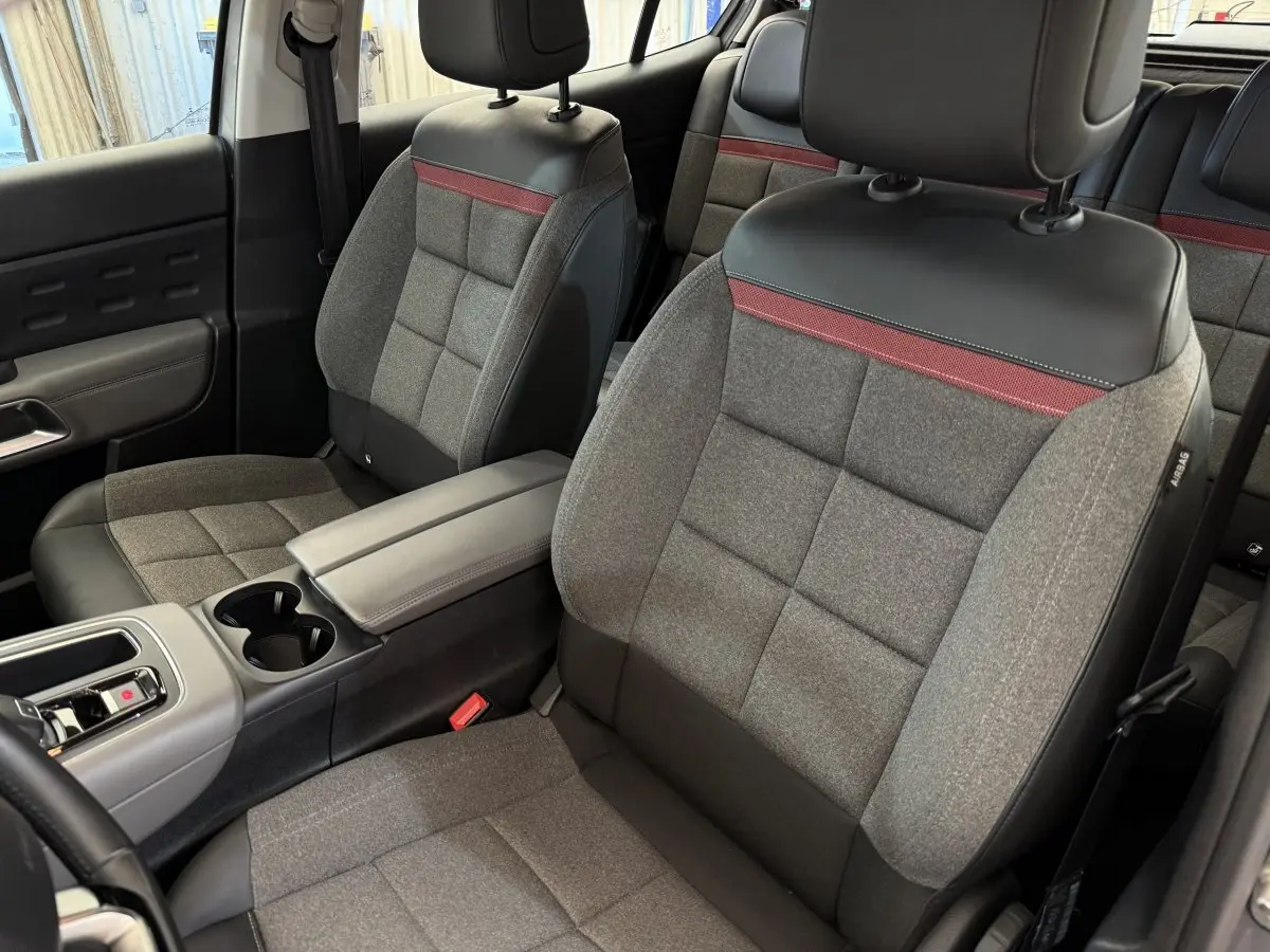 Intérieur du Citroën C5 Aircross 2020, sièges avant gris clair avec bande rouge et accoudoir central noir.