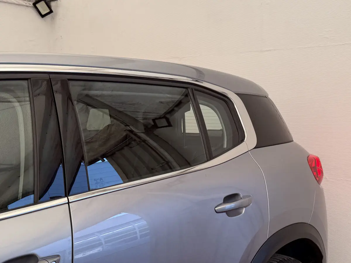 Vue côté droit arrière d'un Citroën C5 Aircross gris clair avec vitres teintées et contour de fenêtres chromé.