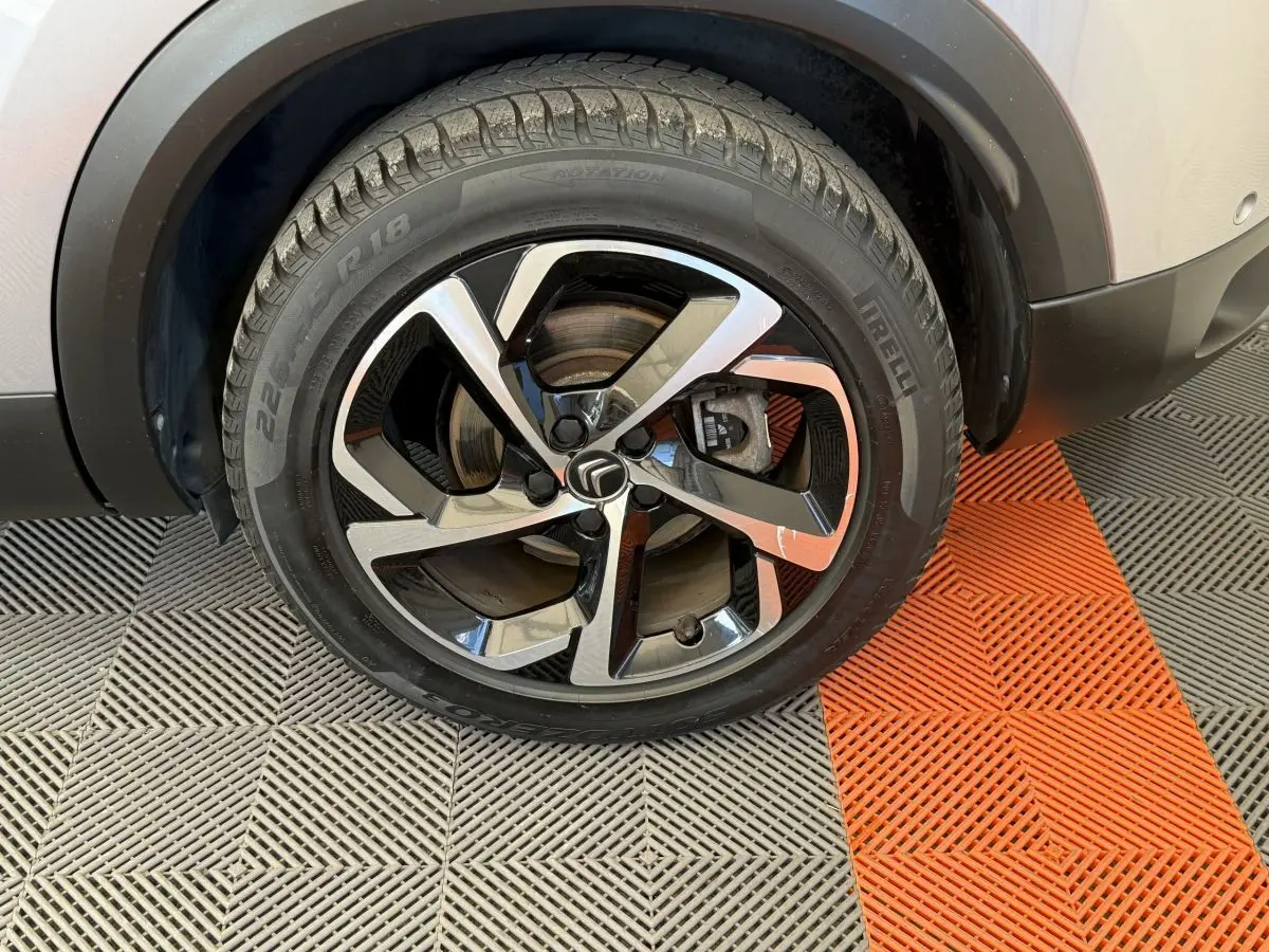 Gros plan sur la roue avant droite gris clair du Citroën C5 Aircross avec jante alliage noire et argentée.