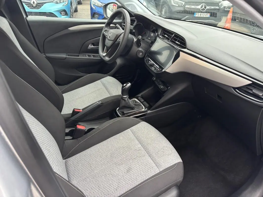Vue intérieure côté conducteur de l’Opel Corsa gris clair 2024, montrant sièges bi-ton, volant multifonctions et écran tactile.
