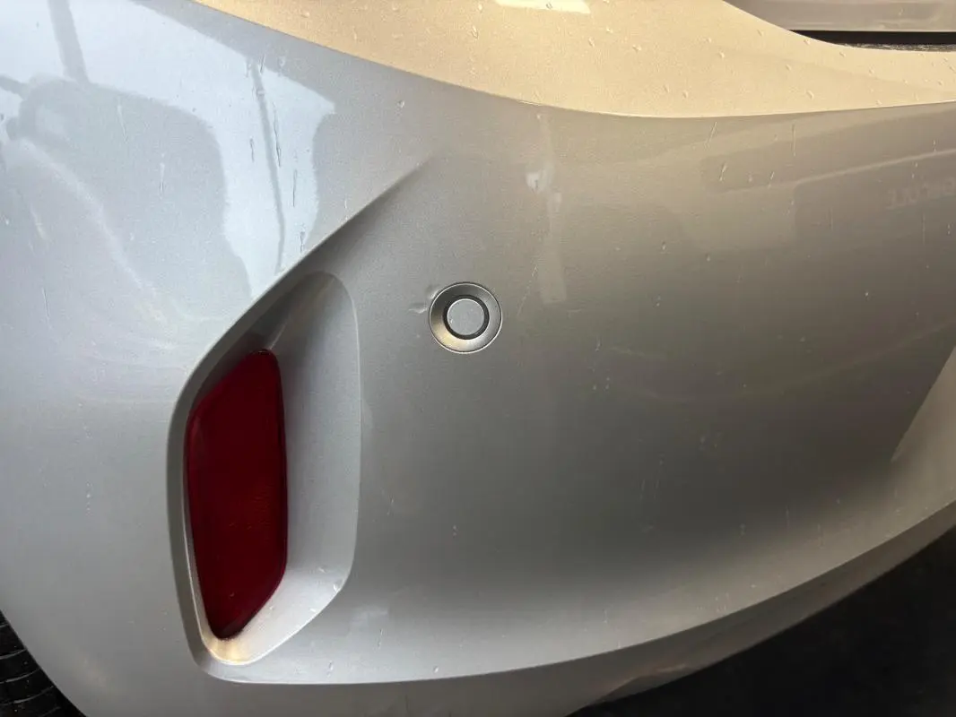 Gros plan sur le pare-chocs arrière gris clair de l'Opel Corsa 2024 avec capteur de recul et feu rouge intégré.