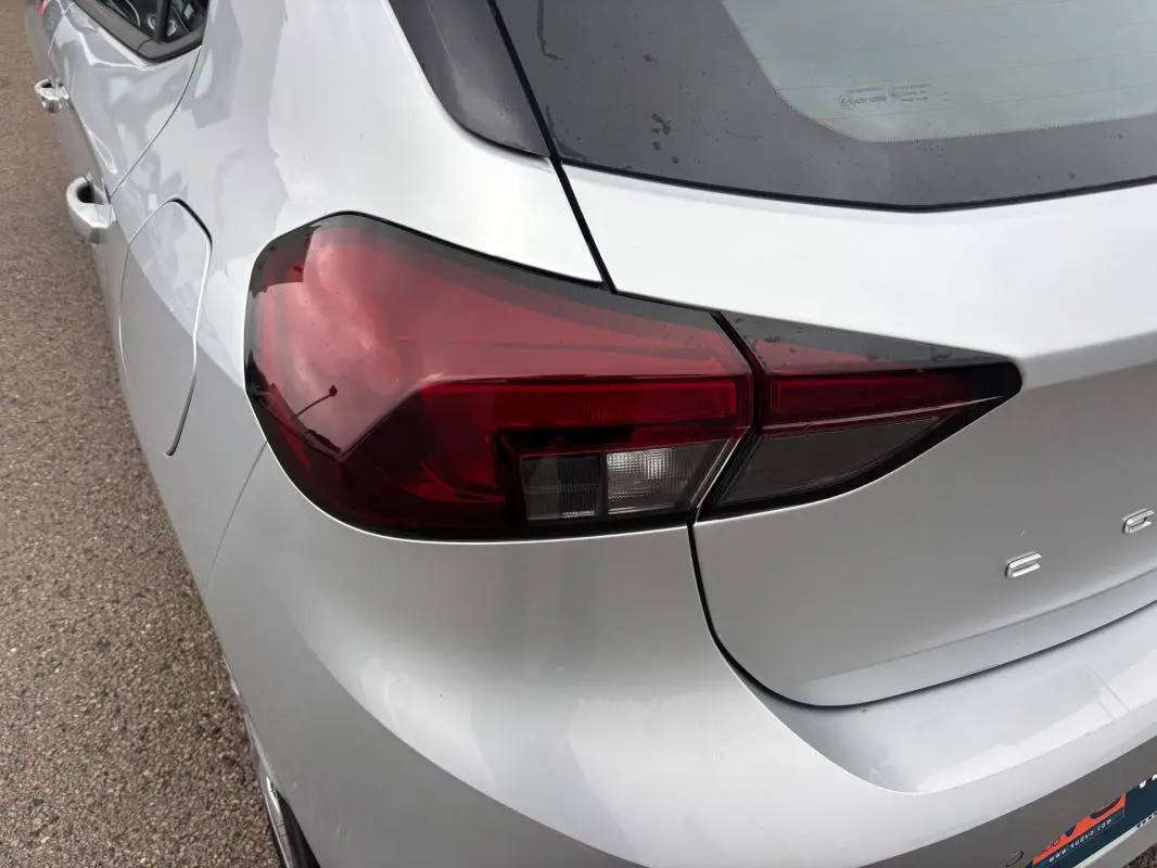 Gros plan sur le feu arrière gauche d’une Opel Corsa gris clair 2024, avec une partie de la malle visible.