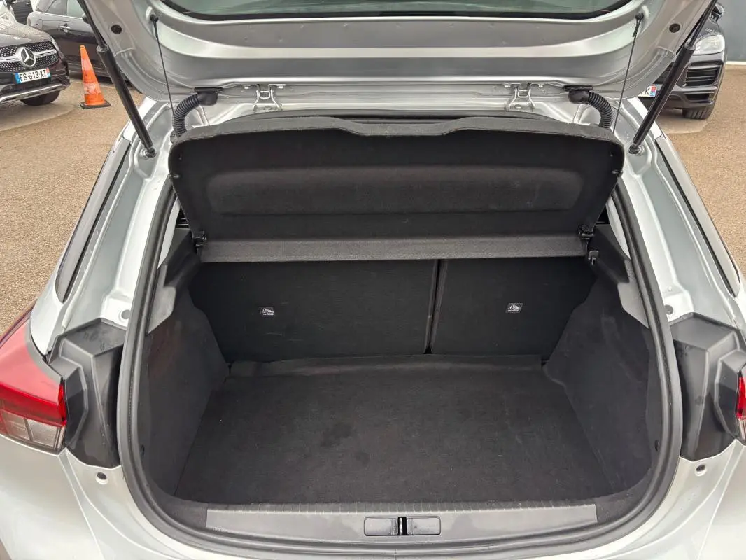 Coffre ouvert vu de l'arrière d'une Opel Corsa gris clair 2024, montrant l'espace de rangement vide.