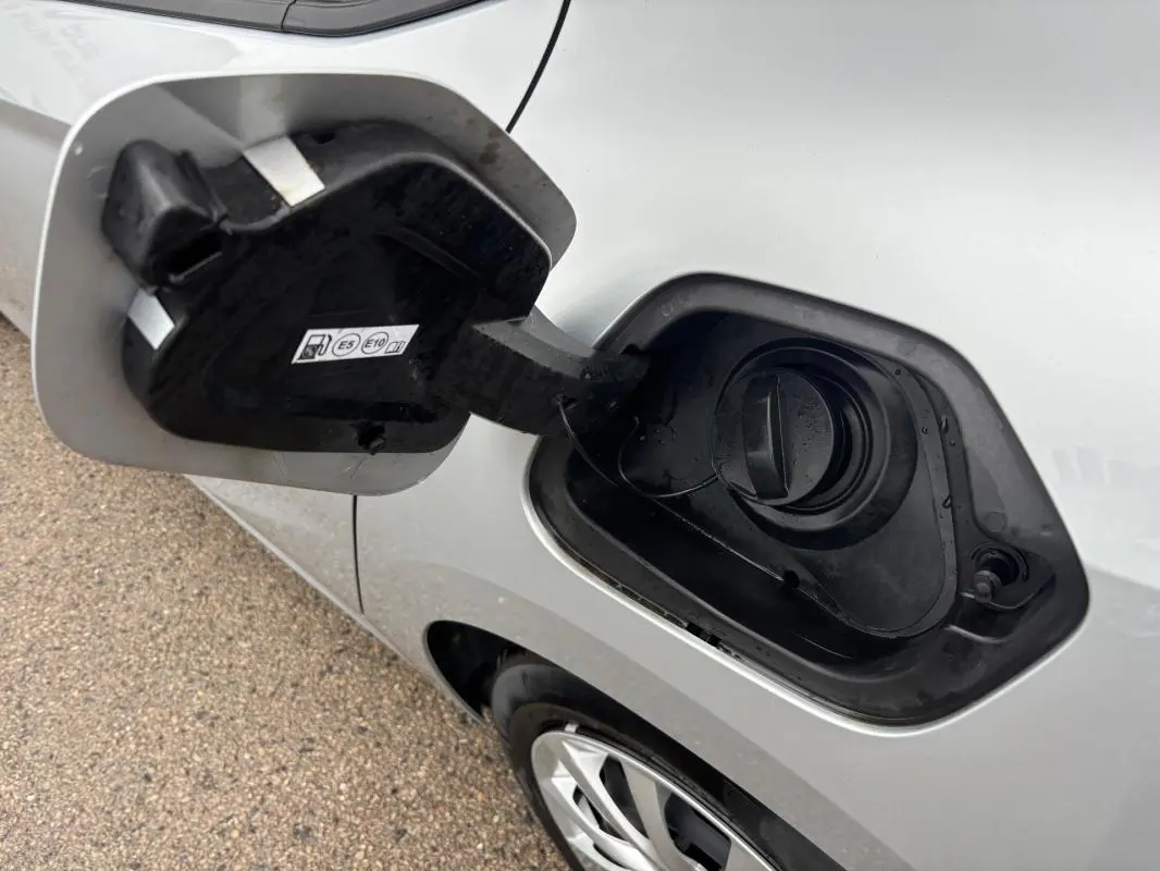 Vue rapprochée du bouchon de réservoir essence ouvert sur le côté gauche d'une Opel Corsa gris clair 2024.