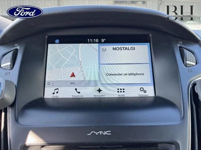 Écran tactile central du tableau de bord de la Ford Focus blanc Glacier, affichant la navigation et la radio NOSTALGI.