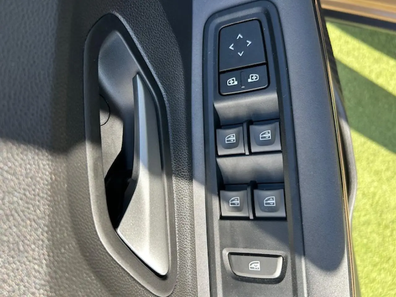 Gros plan sur la commande des vitres électriques et des rétroviseurs côté conducteur de la Dacia Sandero III Stepway beige Safari.