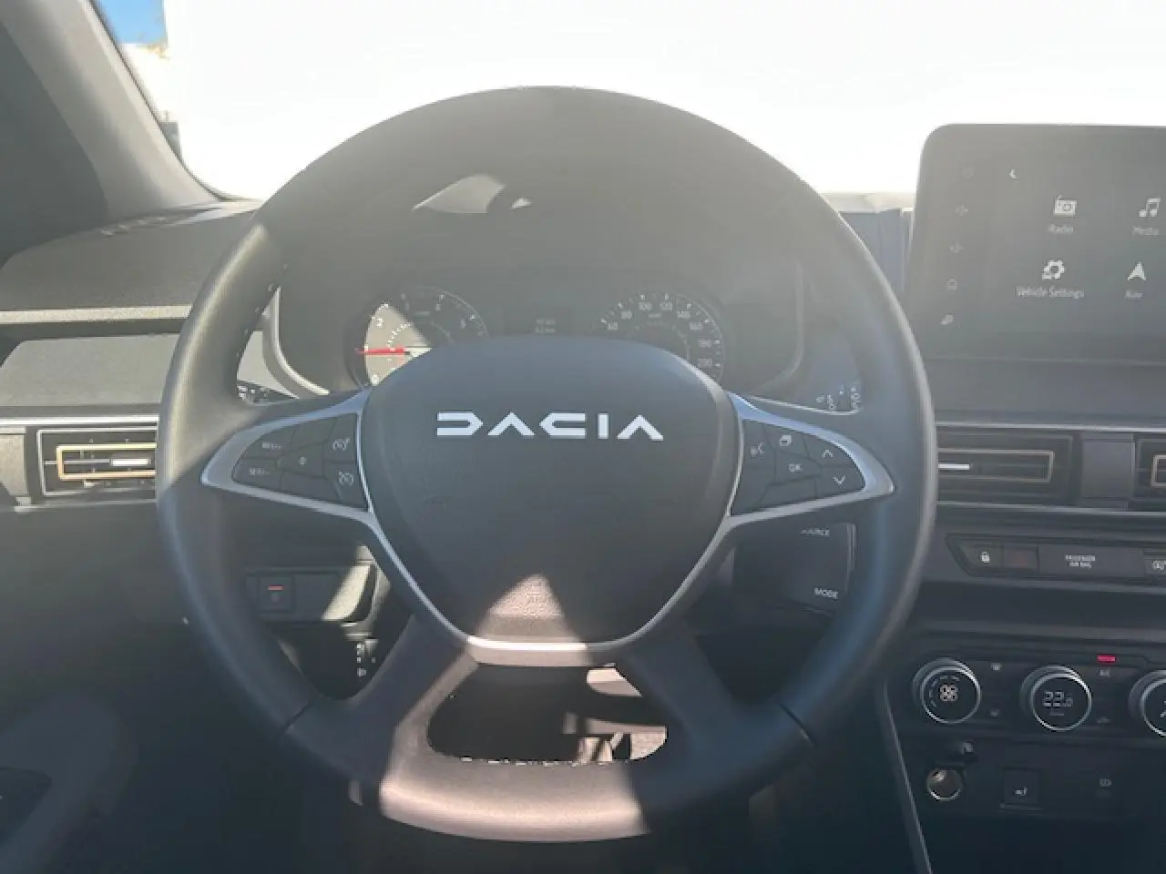 Vue centrée sur le volant noir du Dacia Sandero III Stepway avec tableau de bord et écran tactile visible.