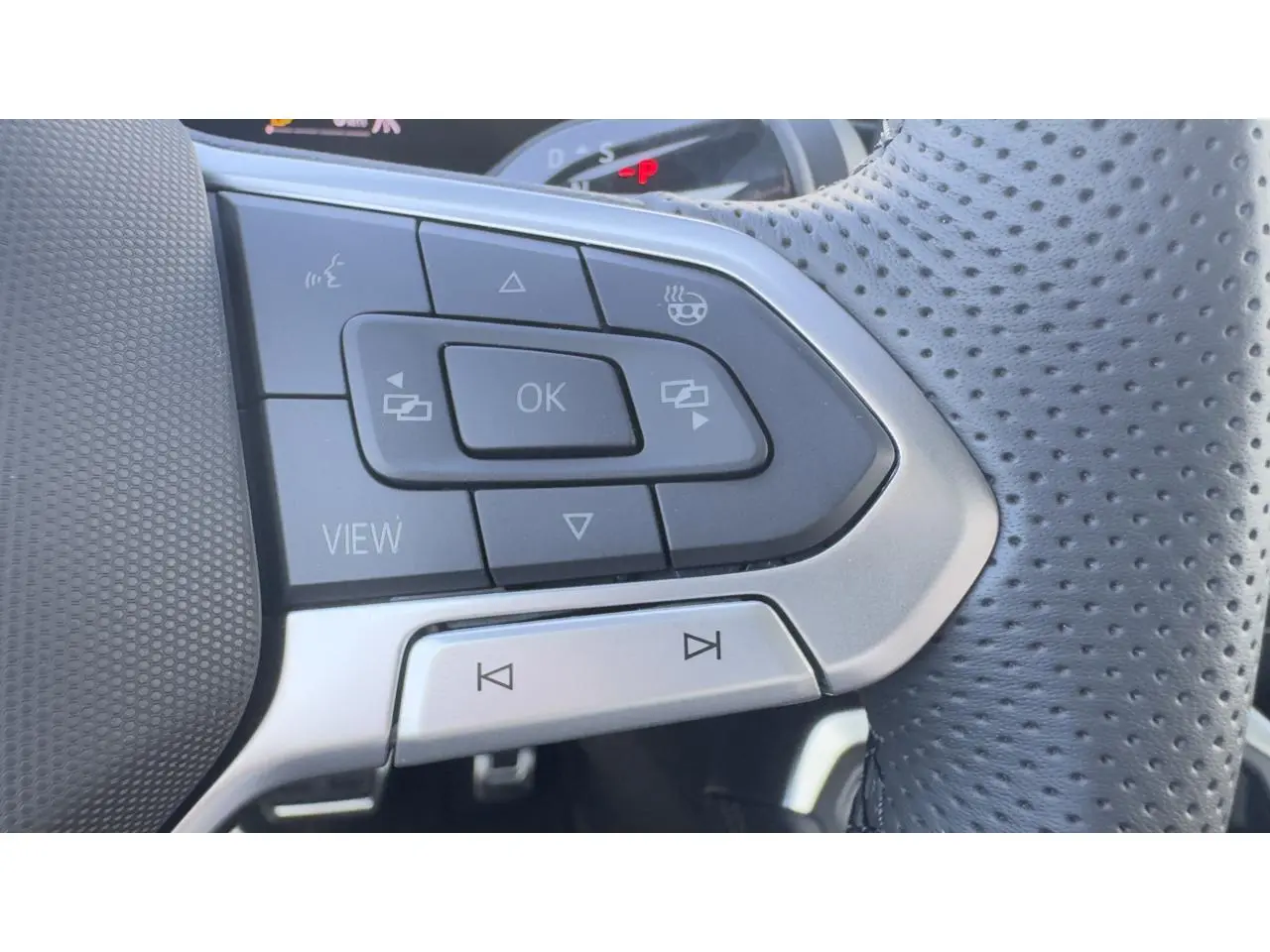 Gros plan sur les commandes multifonctions du volant cuir perforé du Volkswagen T-Roc noir, version R-Line.