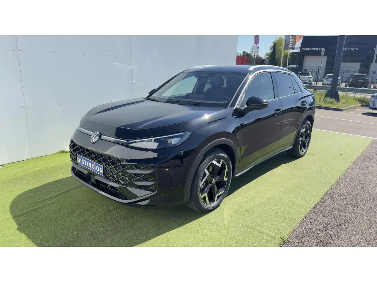 Volkswagen T-Roc noir en 3/4 avant droit, avec jantes 18 pouces et toit panoramique visible sous lumière naturelle.