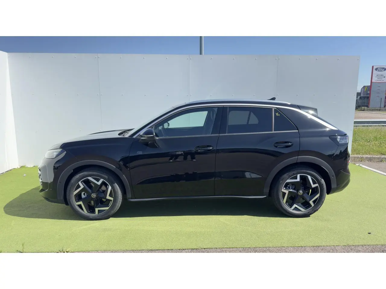 Vue de profil côté gauche d'un Volkswagen T-Roc noir avec jantes 18 pouces et toit panoramique.