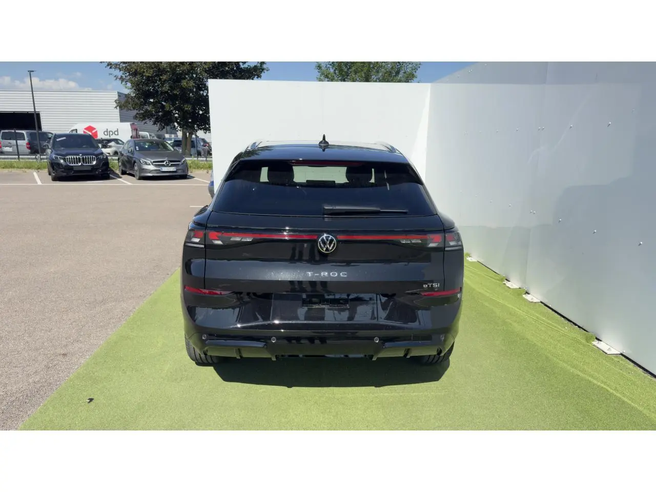 Vue arrière d'un Volkswagen T-Roc noir 2026 avec feux arrière LED reliés par un bandeau lumineux rouge.