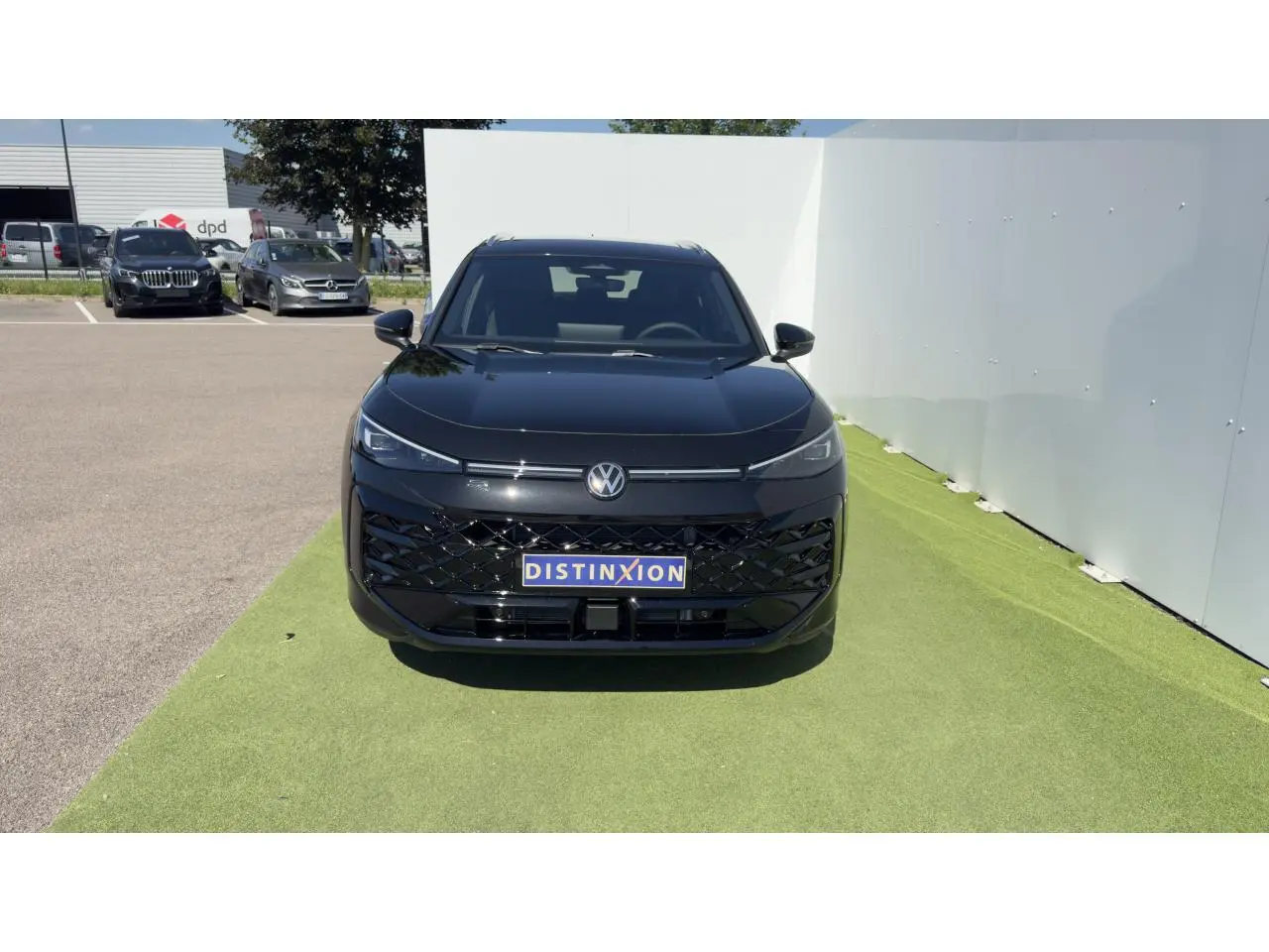 Vue frontale d'un Volkswagen T-Roc noir avec calandre noire brillante et logo VW éclairé sur fond clair.