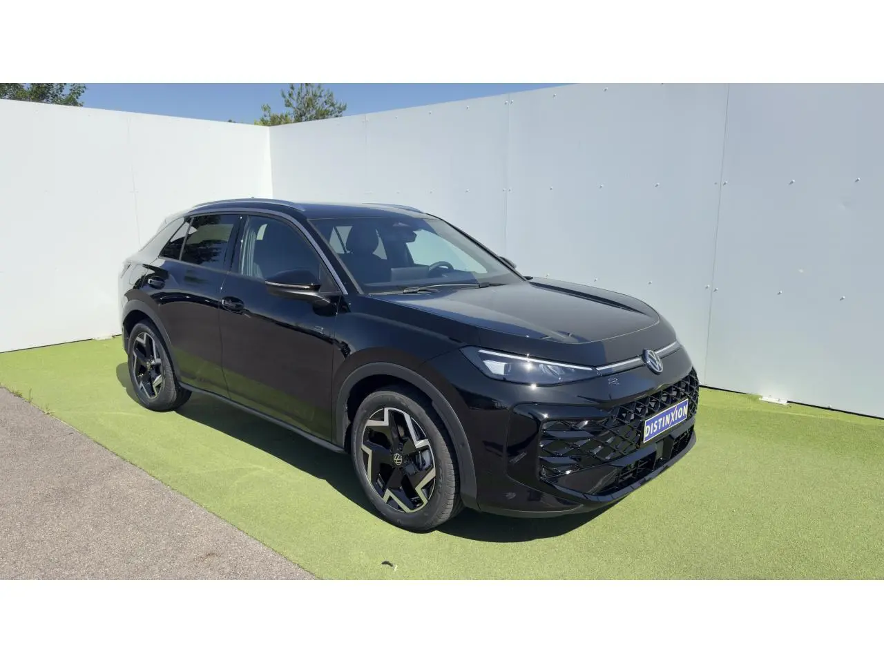 Volkswagen T-Roc noir en 3/4 avant droit, avec jantes 18 pouces et toit panoramique visible.