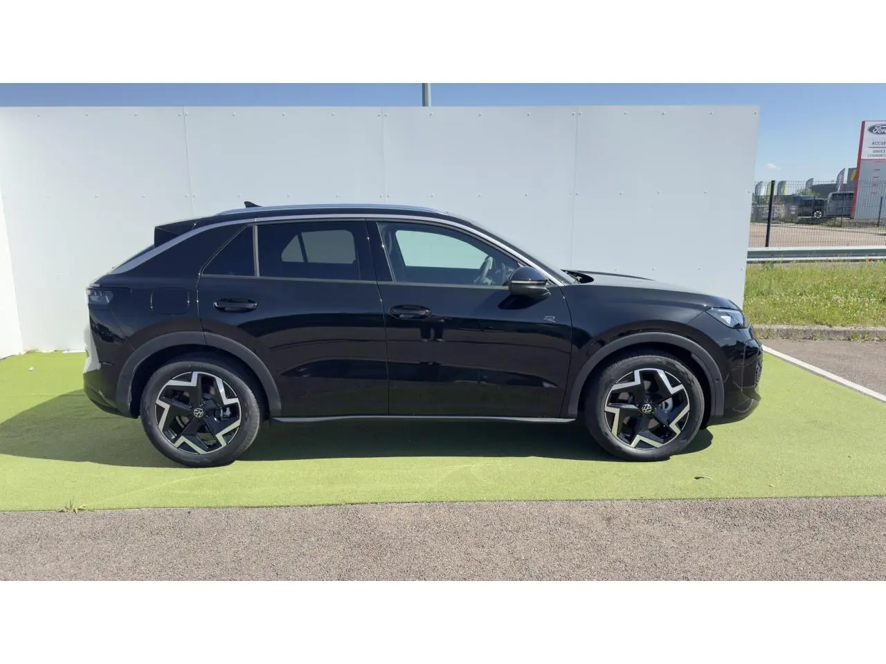 Vue latérale droite d'un Volkswagen T-Roc noir avec jantes 18 pouces et toit noir sur fond extérieur clair.