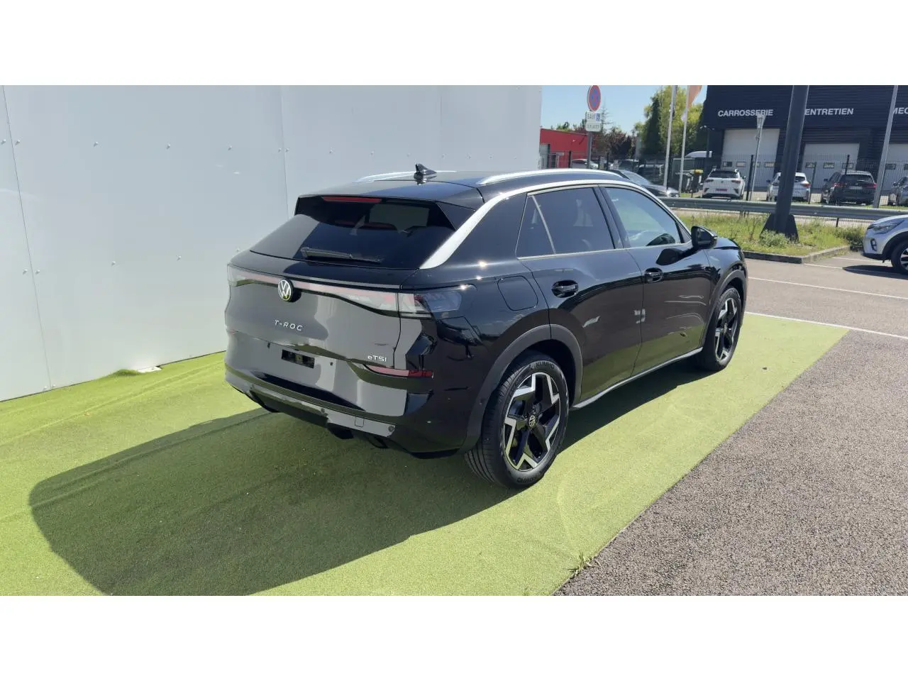 Volkswagen T-Roc noir en 3/4 arrière droit, avec toit noir et jantes 18 pouces Coventry visibles.