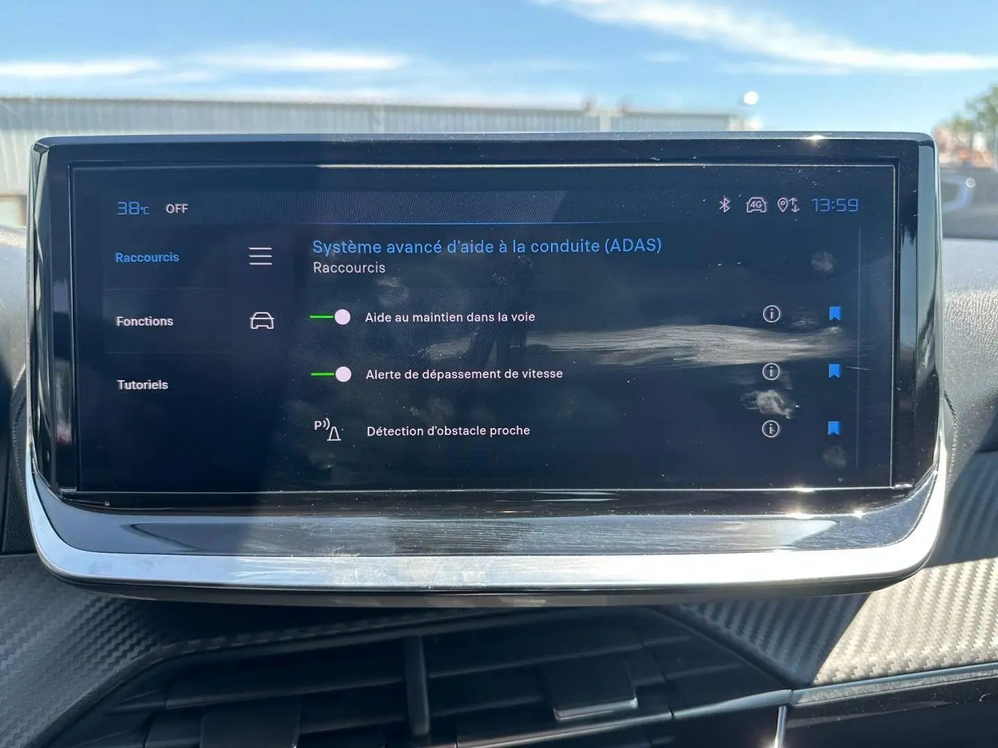 Écran tactile du système d’aide à la conduite sur tableau de bord de Peugeot 208 gris Artense, vue frontale.