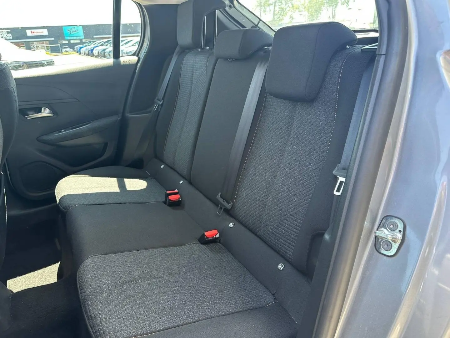 Vue de la banquette arrière côté droit de la Peugeot 208 2025 gris Artense avec tissu noir et ceintures visibles.