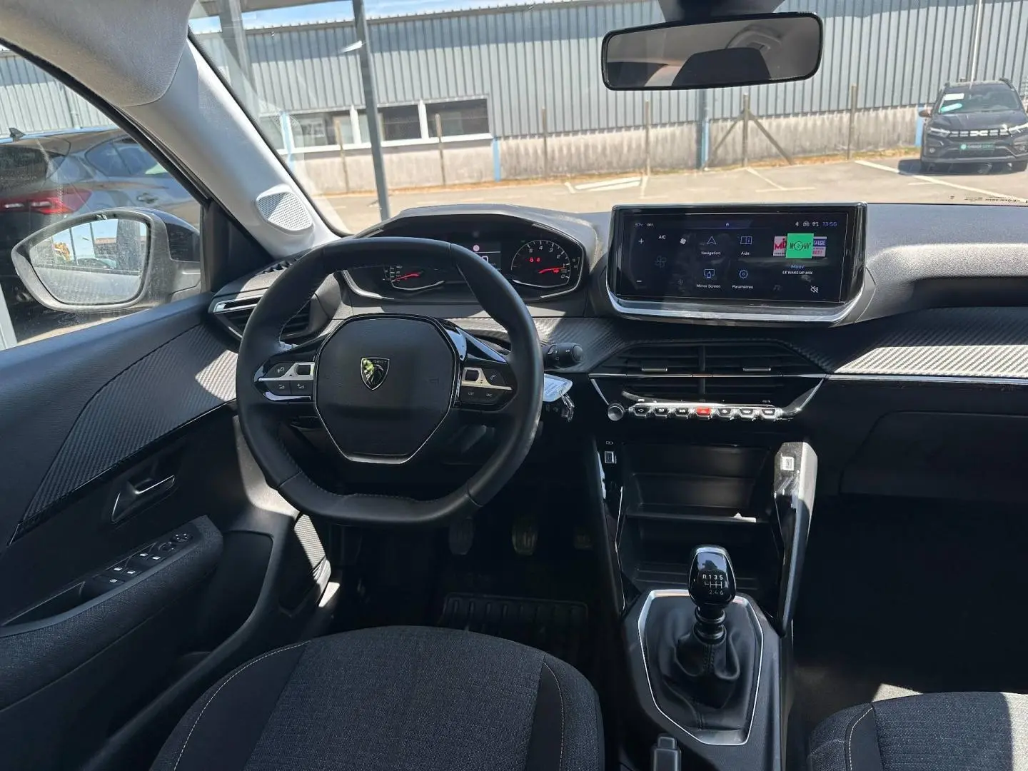 Vue intérieure avant de la Peugeot 208 1.2 100ch Style avec volant compact, écran tactile et levier de vitesses manuel.