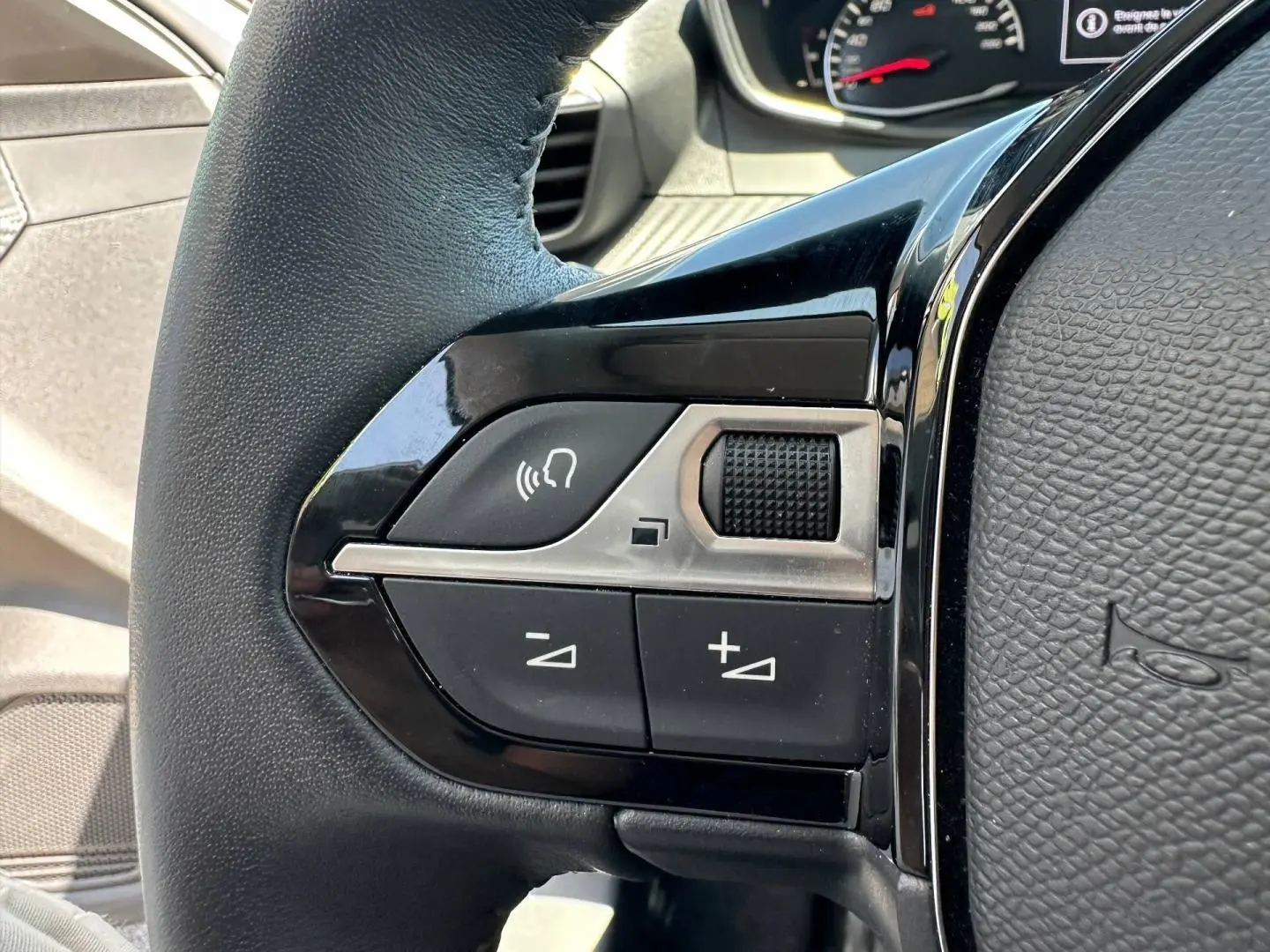 Gros plan sur les commandes audio au volant noir de la Peugeot 208 1.2 100ch Style, intérieur gris.