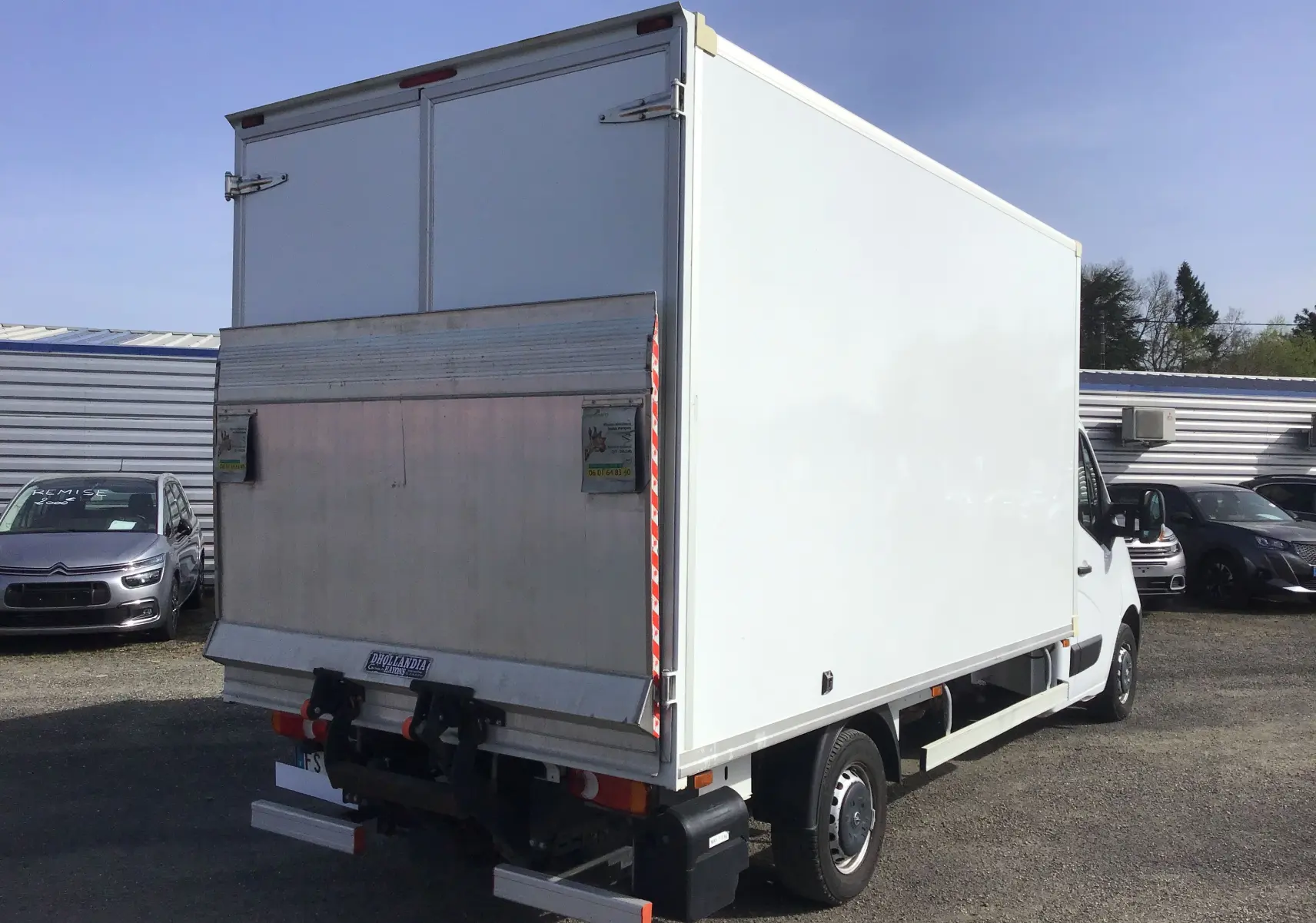 Vue 3/4 arrière droite d’un utilitaire blanc Opel Movano Chassis Cabine avec hayon élévateur métallique déployé.