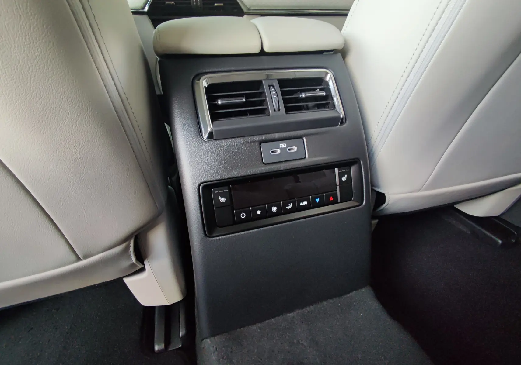 Console arrière avec commandes de climatisation et ports USB du Mazda CX-80 gris foncé, vue centrée entre les sièges avant.